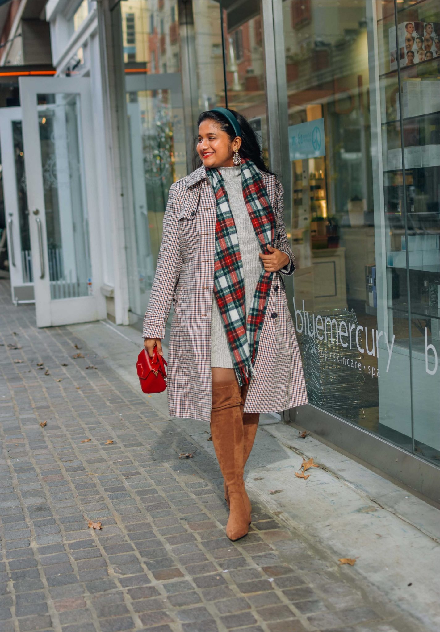 Wearing AE Sweater dress,Talbots polished plaid trench coat,Amazon OTK boots,J.crew Tartan scarf-Holiday Outfit ideas |Cute Holiday Outfit Ideas by popular Maryland modest fashion blog, Dreaming Loud: image of a woman wearing a AE Sweater dress, Amazon N.N.G OTK boots, J.crew Tartan scarf, and holding a lulu Guinness bag.