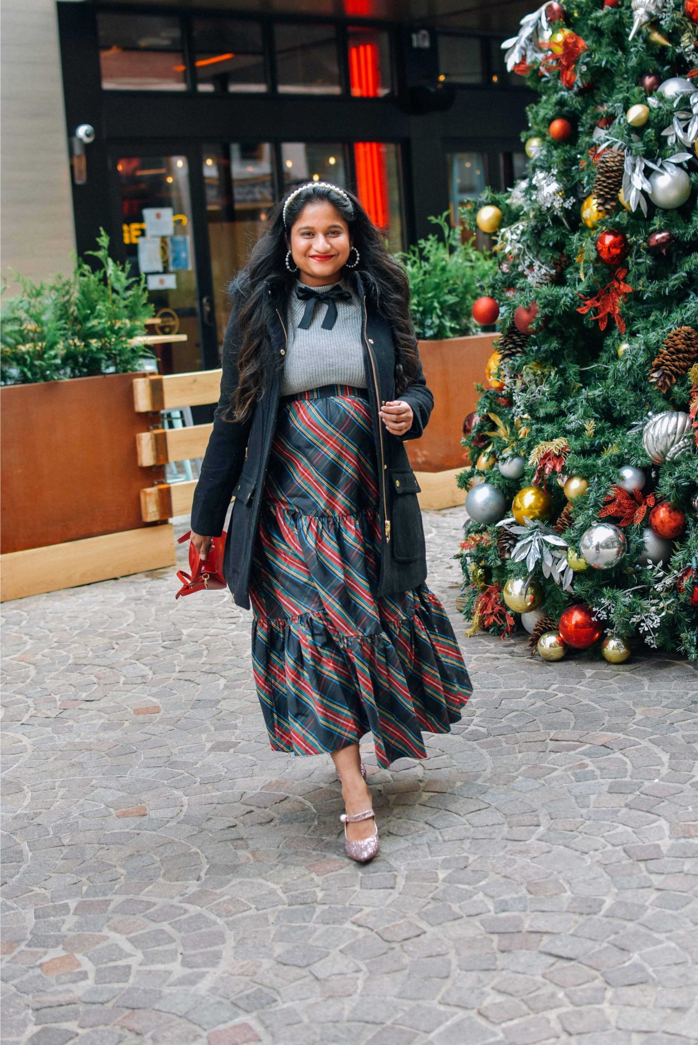 Wearing J.crew Chateau parka in Italian stadium-cloth wool in black, J.crew Tartan tiered sirt, bow sweater, Pink sequin pumps-Maternity Holiday Outfit ideas